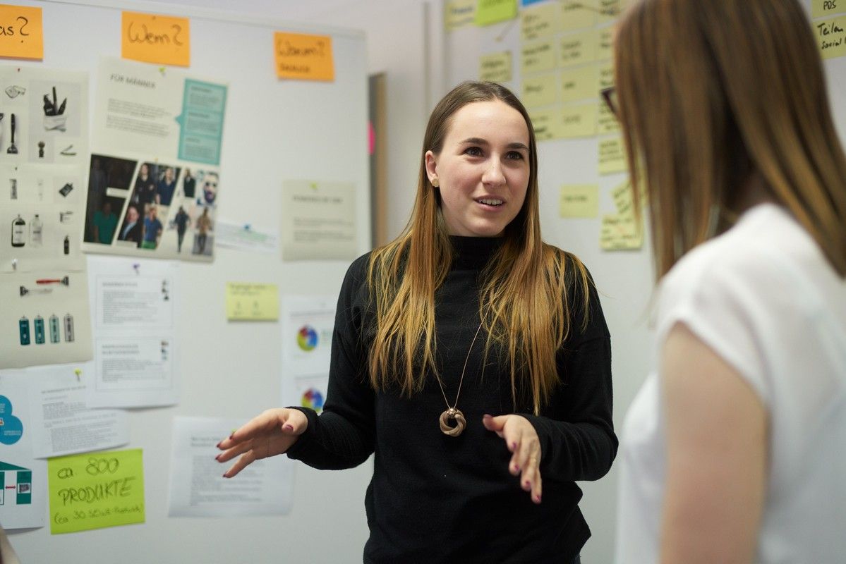 Junge IT-Consultant steht vor Board mit Post-its und erklärt