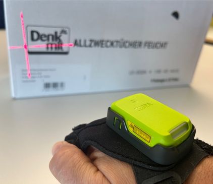 Eine Hand mit Handrücken-Scanner scannt dm-Produkt in der Logistik
