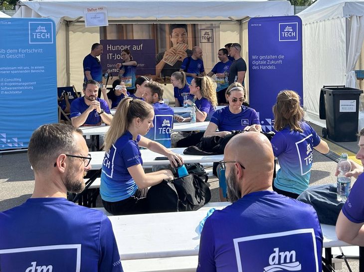 dmTECH Mitarbeitende im Laufshirt erfrischen sich vor dem dmTECH Stand