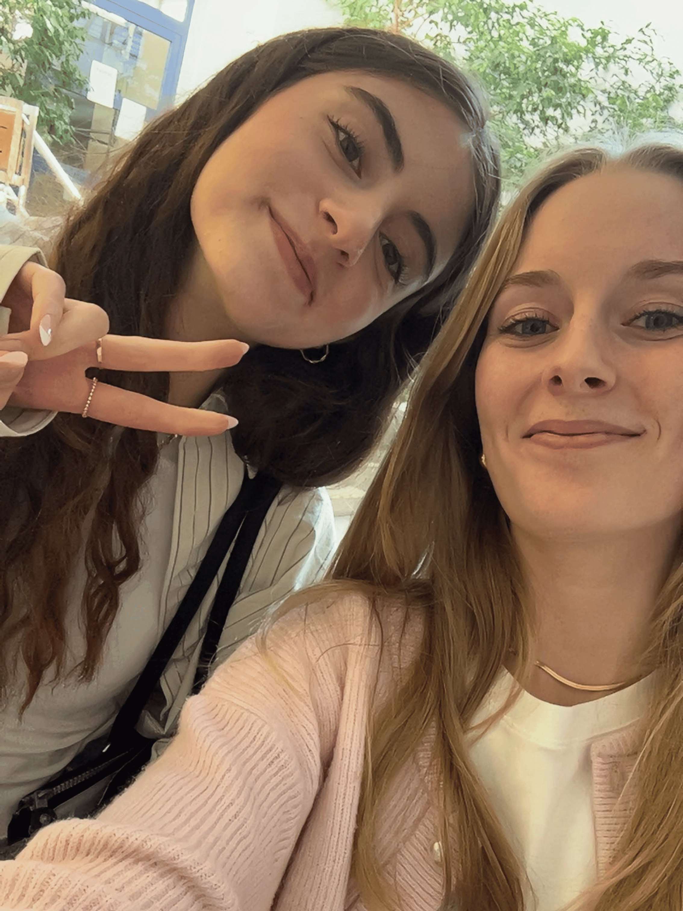 Zwei junge duale Studentinnen machen ein Selfie, die linke formt mit der Hand ein Friedenszeichen