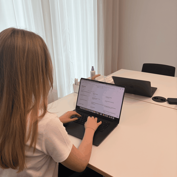 Eine duale Studentin sitzt mit dem Rücken zur Kamera und tippt auf einem Laptop, der einen Kursplan anzeigt