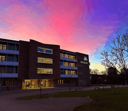 Das dm-dialogicum mit beleuchteten Fenstern unter einem pink-violett-blauen Abendhimmel