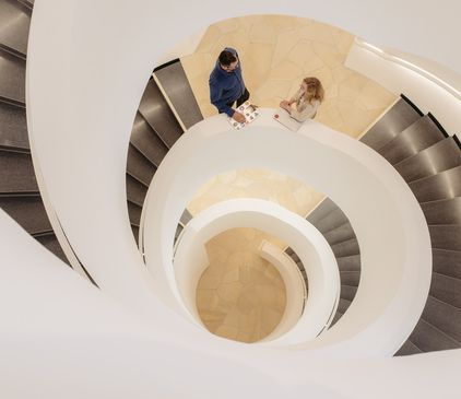 Spiralförmiges Treppenhaus im dialogicum von oben mit zwei Mitarbeitenden