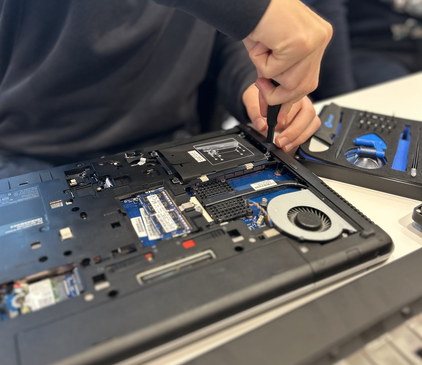 Ein bereits aufgeschraubter Laptop wird noch weiter auseinandergebaut.