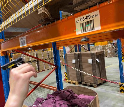 dmTECH Mitarbeiter scannt mit dem Ringscanner einen Barcode am Regal