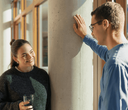 Junge IT-Mitarbeiterin und junger IT-Mitarbeiter unterhalten sich auf dem Flur im dm-dialogicum
