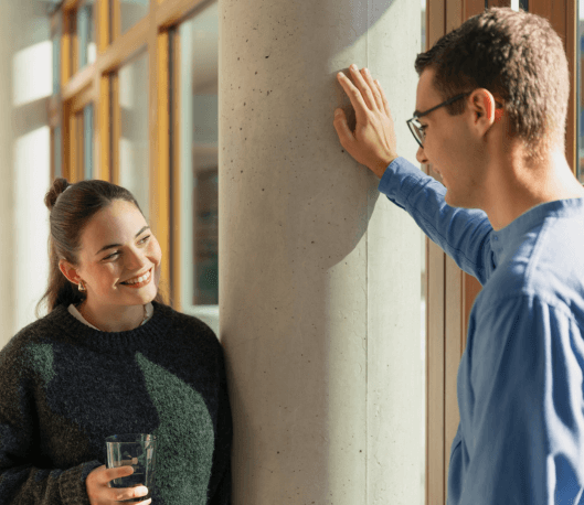 Junge IT-Mitarbeiterin und junger IT-Mitarbeiter unterhalten sich auf dem Flur im dm-dialogicum