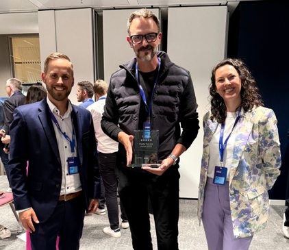 Drei dmTECH Mitarbeitende posieren stolz mit dem Digital Service Award 2025