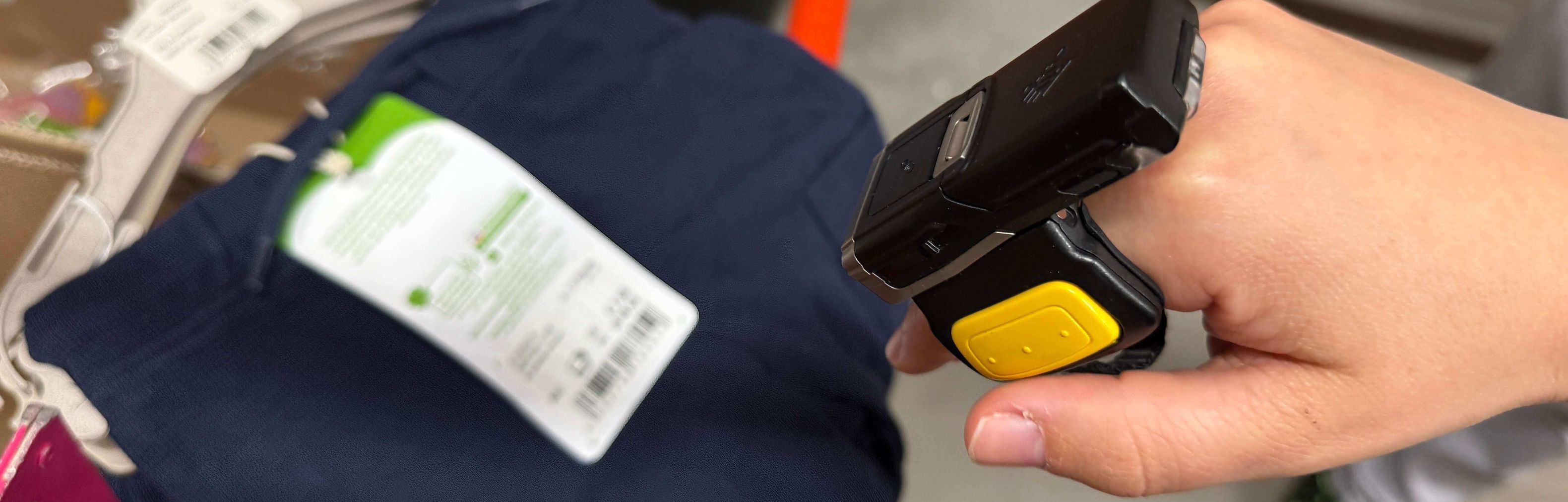 dmTECH Mitarbeiter scannt mit dem Ringscanner einen Barcode eines Textilartikels