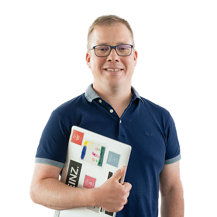Junger Mann mit Brille und Laptop im Arm lächelt