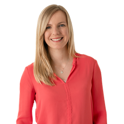 Junge, blonde Frau in roter Bluse lächelt in Kamera