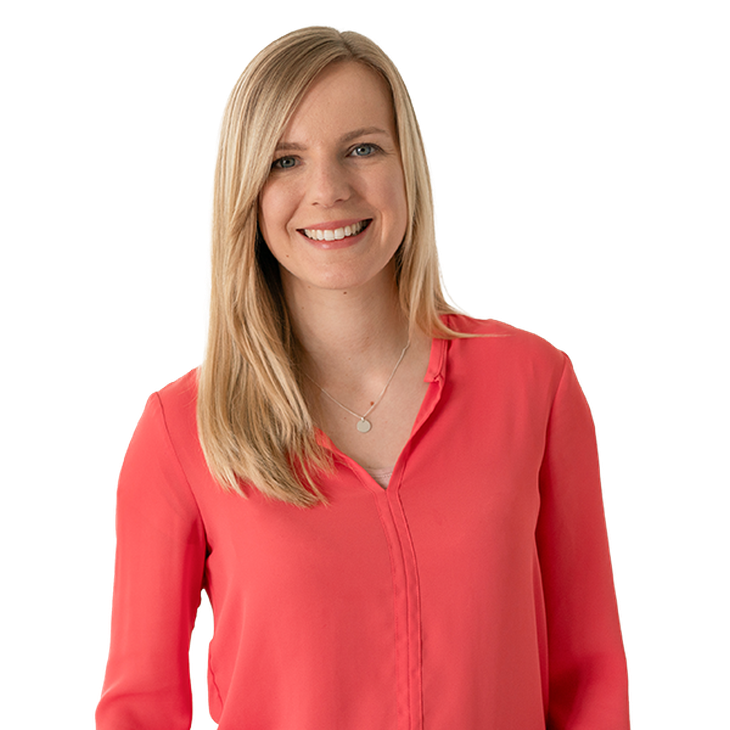 Junge, blonde Frau in roter Bluse lächelt in Kamera
